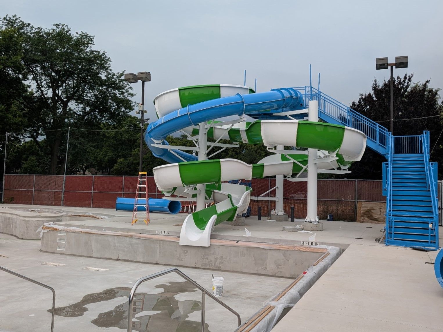 Blue and green spiral water slides with blue stairs at Rehm Park & Pool.