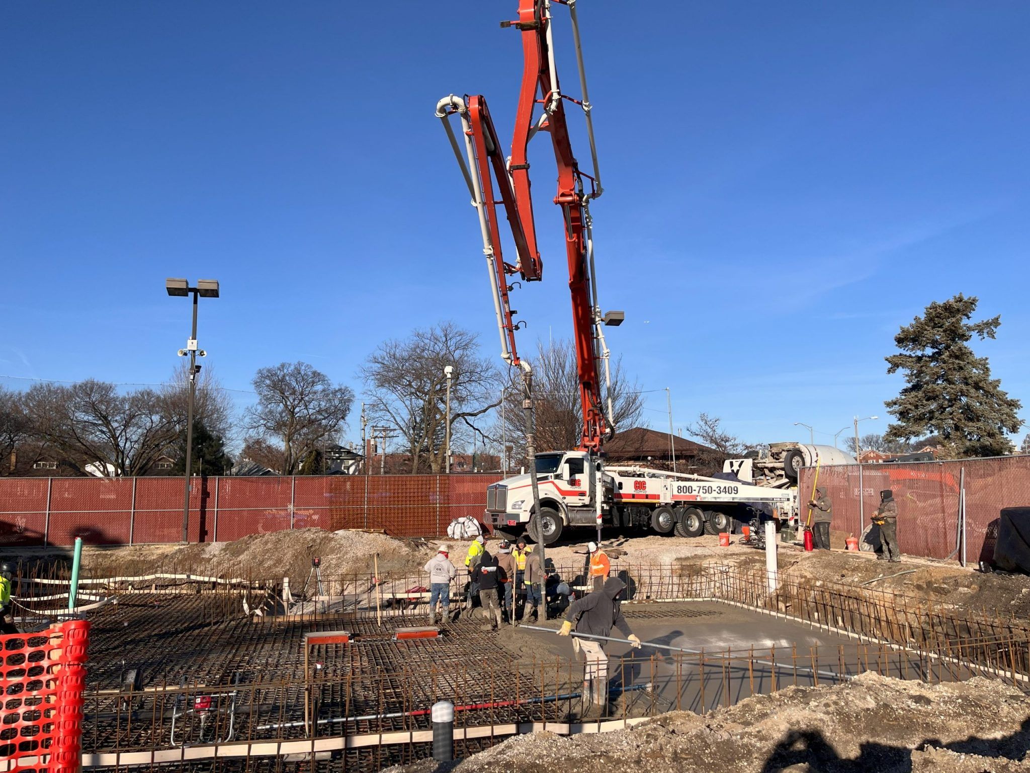 Construction workers pour concrete using a pump truck at the Rehm Park & Pool site.
