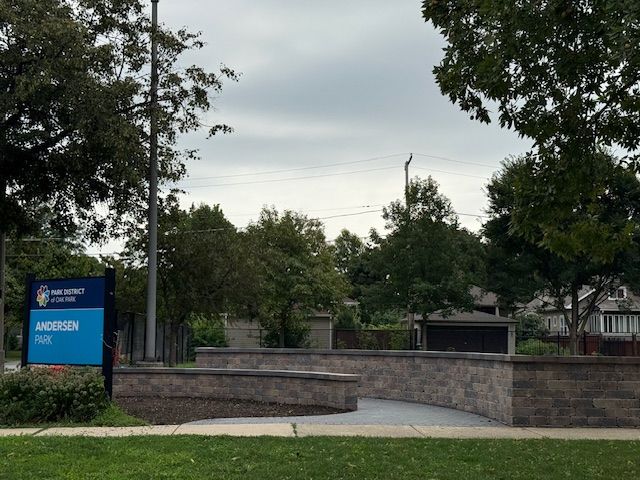 Sign for Andersen Park, part of the Park District of Oak Park, with a stone wall and pathway.