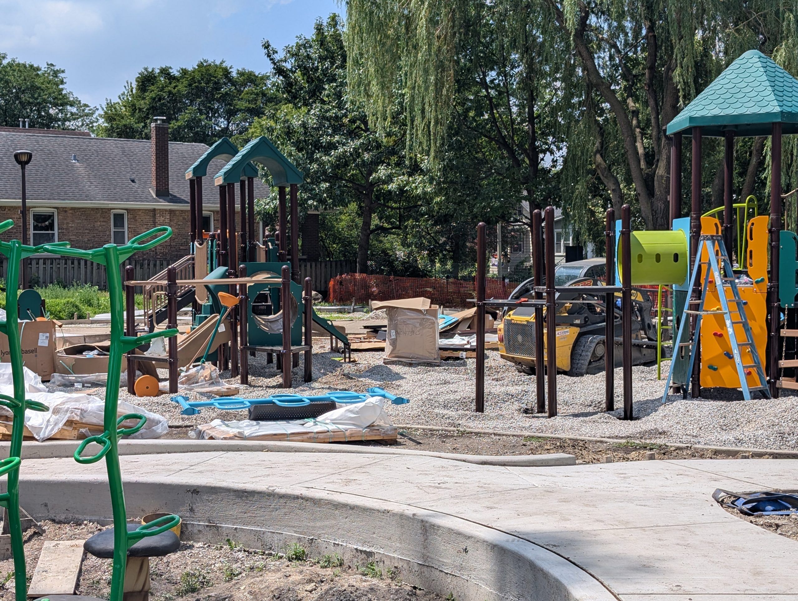 Playground construction at Andersen Park, featuring new equipment, materials, and a skid steer loader.