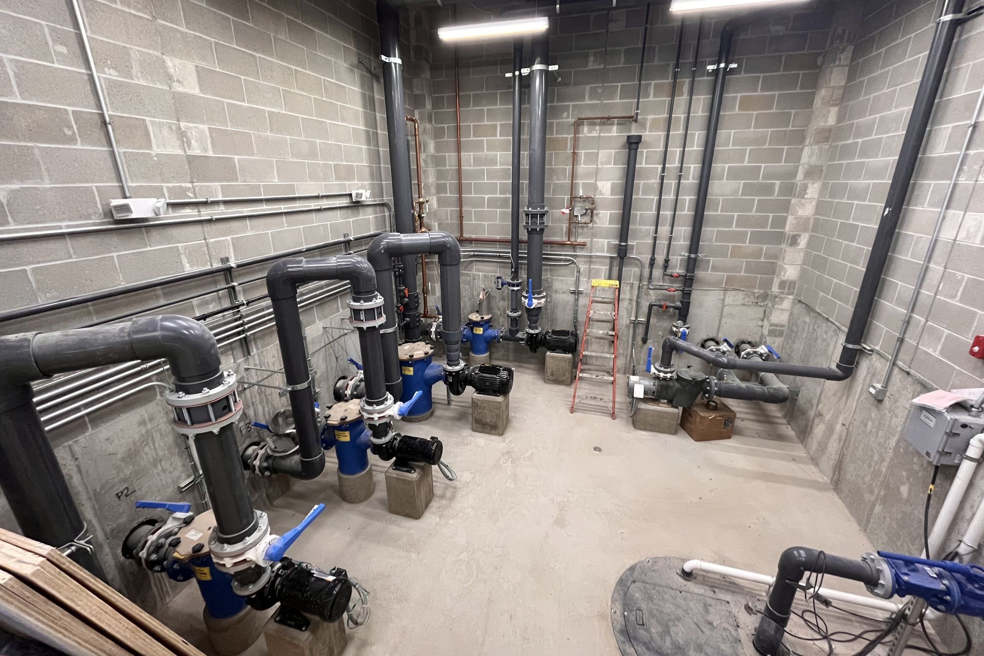 Industrial pumps and piping system in a concrete room at Rehm Park & Pool.