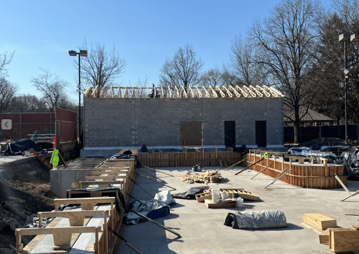 Construction of Rehm Park & Pool building with cinder block walls and wooden roof trusses. Foundation work is visible in the