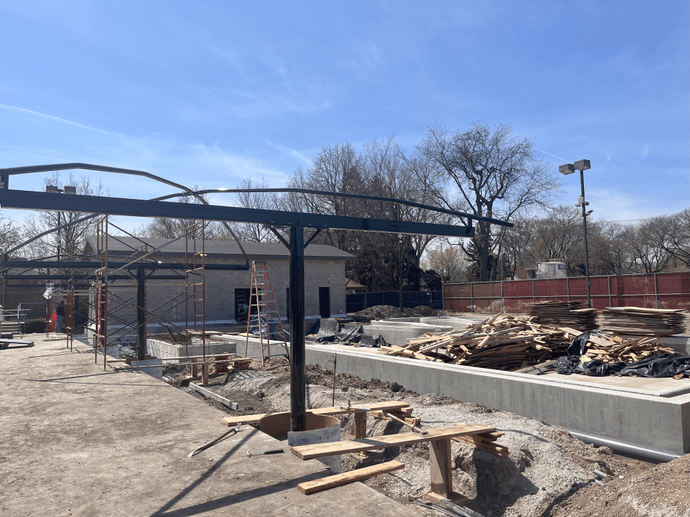 Construction of a shade trellis structure at Rehm Park & Pool with scaffolding and building materials visible.