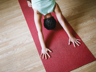 Person in downward-facing dog pose on a red yoga mat.