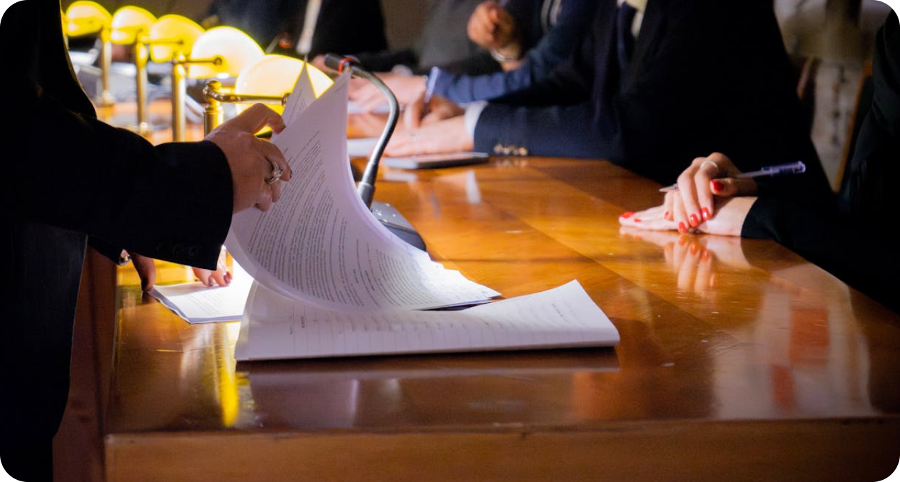Hands of commissioners reviewing documents at a polished wooden table during a meeting.