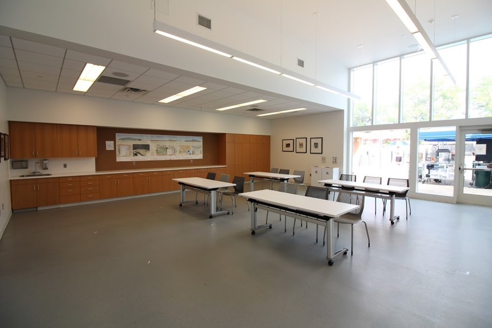 room with large windows and wood cabinets with four tables in the center