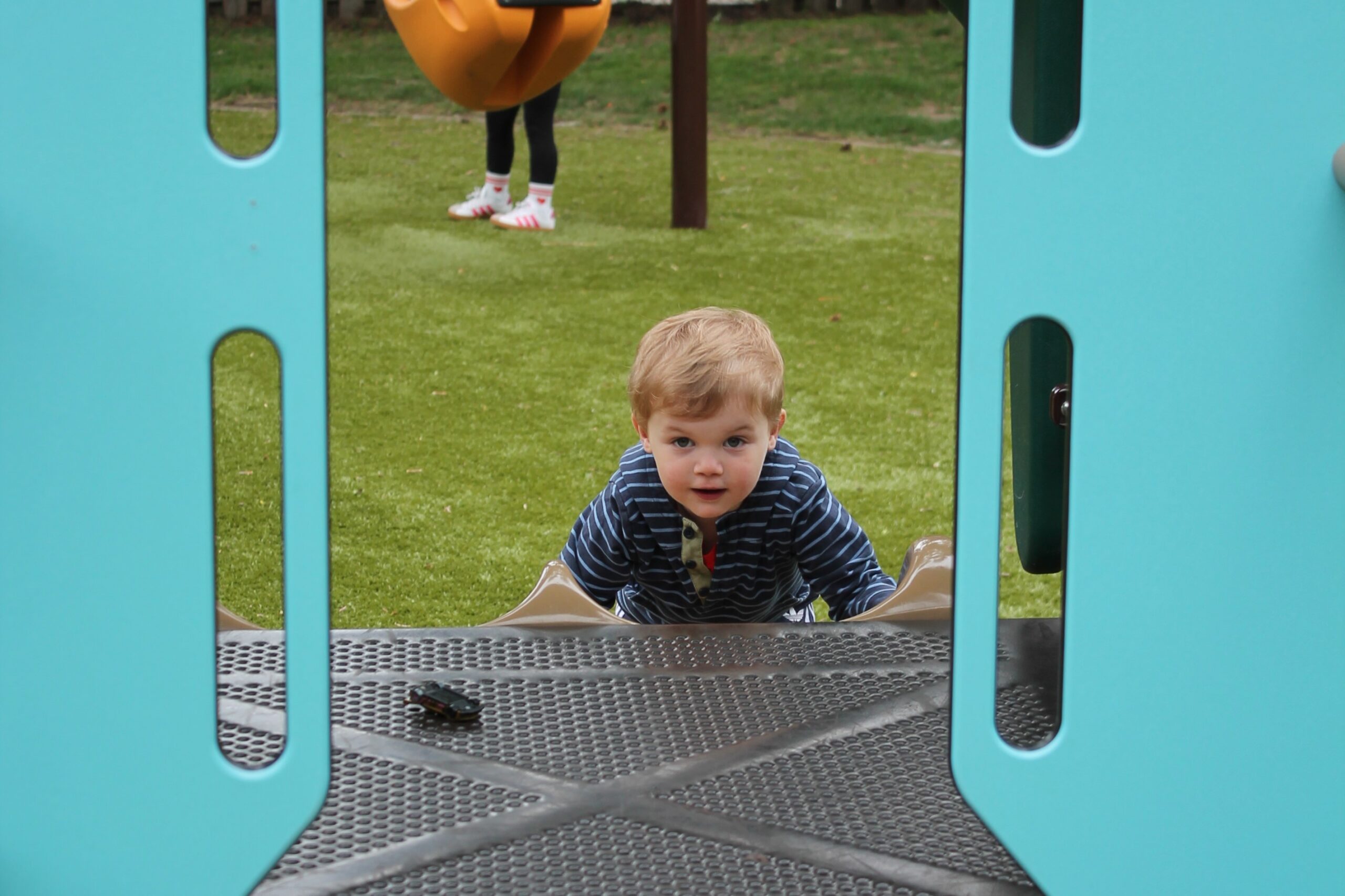 boy peeks between two blue playground walls