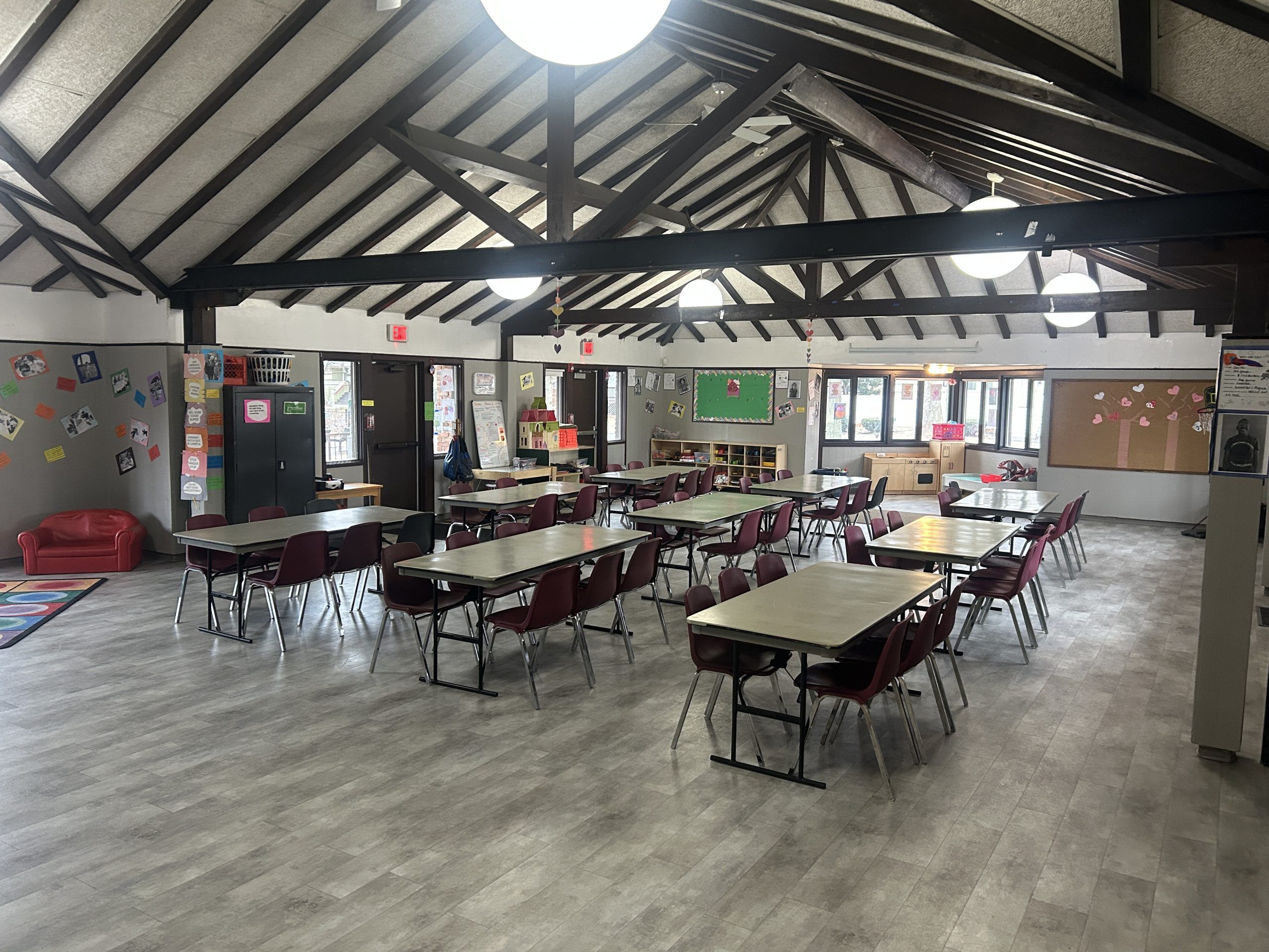 room with wood beams and nine tables with chairs on either side