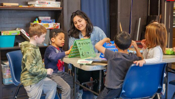 instructor plays board game with clubhouse students