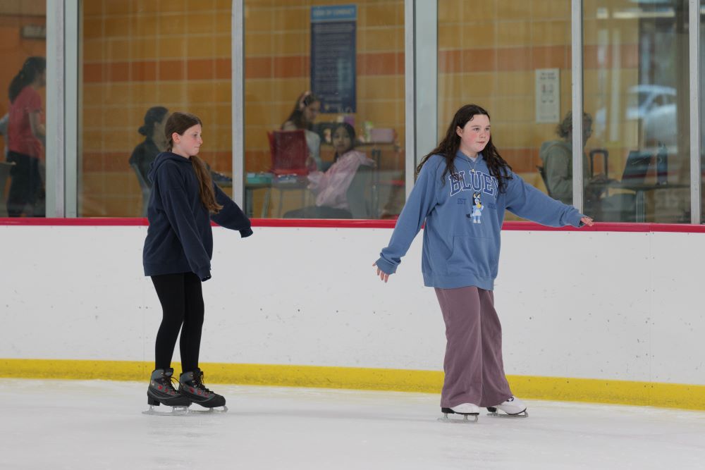 two teens skate around the rink