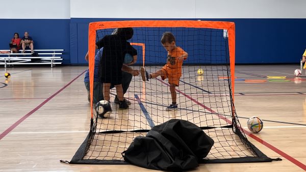 a young boy practices kicking a goal